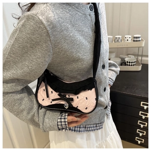 Detailed view of pink pleated fabric with black bows and rabbit prints on shoulder bag