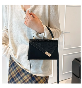 Détail du sac noir structuré avec motif crocodile asymétrique et fermoir doré élégant