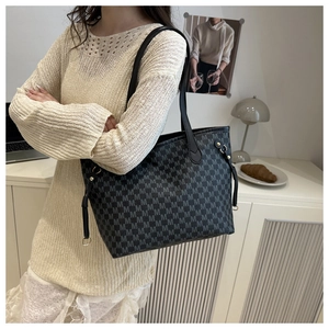 Detail of monogram patterned tote bag with adjustable shoulder strap and gold hardware