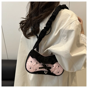 Detail of pink jacquard underarm bag with black lace ruffles and silver heart charm
