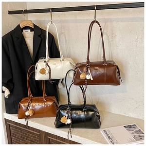 Detail view of large vintage shoulder bags in four colors with glossy finish and charms
