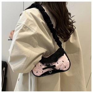 Detail of pink ruffled shoulder bag featuring black bunny prints and a silver heart charm