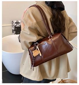 Detail of dark brown glossy bowling bag with silver logo and cute cartoon charm
