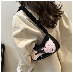 Detailed back view of pink patterned shoulder bag with black bow and heart charm