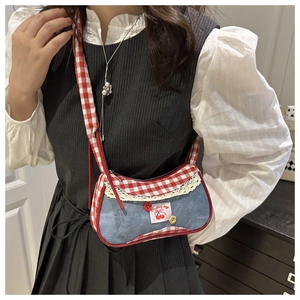 Detail of blue denim shoulder bag with red plaid trim and elegant white lace edges