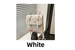 Détail d'un sac à main blanc en cuir PU avec motifs de chien et cerises sur table en bois