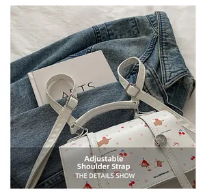 Détail des bretelles réglables en cuir blanc avec boucles argentées sur le sac à dos