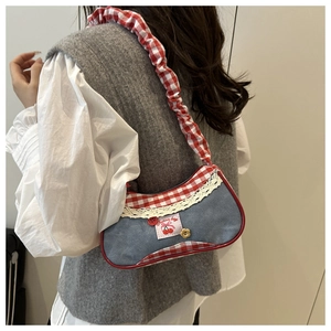 Detail of denim shoulder bag with red gingham trim and cherry patch on lace edge