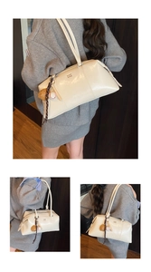 Detailansicht der cremefarbenen Boston-Handtasche mit Ledertextur und Baseball-Anhänger