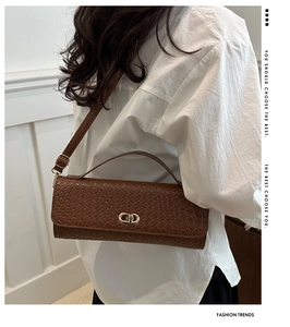 Detail of deep brown woven leather shoulder bag with golden metal buckle and sleek strap