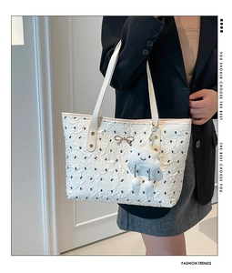 Detailed view of white tote bag with bow patterns and plush cloud pendant accessory