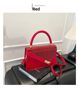 Détail du sac trapèze rouge en cuir gaufré crocodile avec boucle dorée élégante