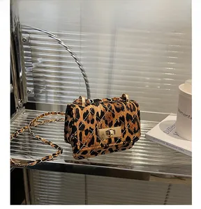 Close-up of leopard print mini square bag featuring gold chain and turn-lock closure