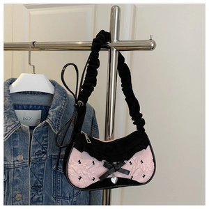 Detail of pink ruffled shoulder bag with black bow, heart charm and scrunchie strap