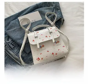 Gros plan détaillé d'un mini sac à dos blanc avec motifs de chiens bruns et cerises