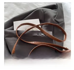 Close-up of brown woven leather strap and golden metal buckle on crossbody bag