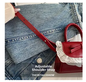 Detail of adjustable red leather strap with metallic buckle on lace handbag