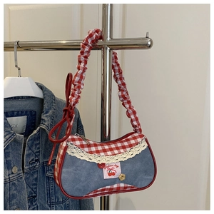 Detail of blue denim bag with red checkered trim, lace edges, and cherry patch