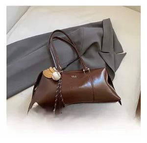Detail of dark brown vintage doctor bag with baseball glove pendant on a grey suit