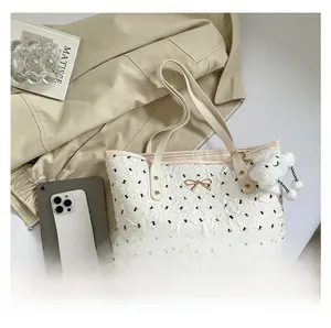 Detail of white tote bag with black bows, golden charm and plush cloud pendant