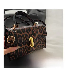 Detail of leopard print faux leather bag featuring a gold twist lock and textured finish