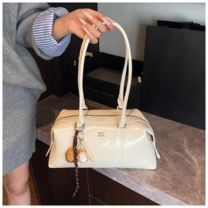 Detail of cream bowling bag with metallic logo and baseball themed charms decoration