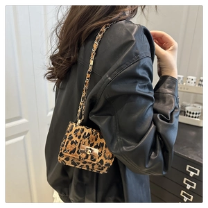 Detail of leopard print crossbody bag with gold chain strap and quilted texture on model