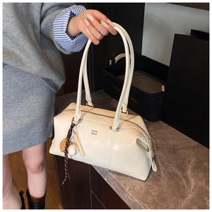 Detail of cream rectangular handbag with logo branding and creative sports pendants