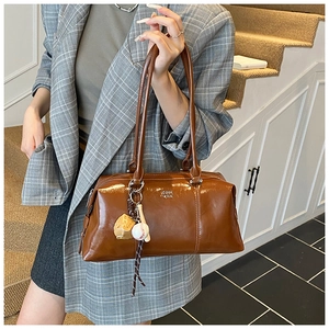 Brown vintage Boston bag with glossy finish and creative baseball charm on model