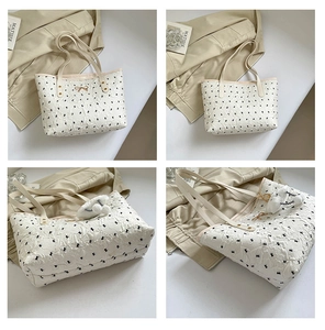 Detail of cream tote bag with black bow embroidery, textured fabric and golden clasp