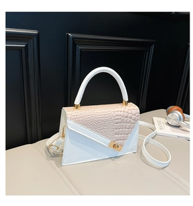 Détail du sac à main en cuir gaufré crocodile blanc et beige avec fermoir doré tournant
