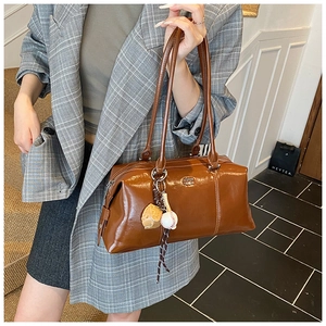 Detail of dark brown leather Boston bag featuring sport charms and embossed logo