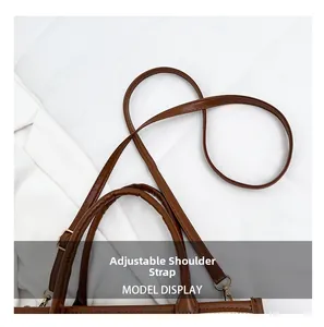 Detail of adjustable shoulder strap and brown handle with bronze metal hooks