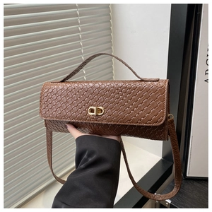 Detailed view of woven leather texture and gold clasp on brown rectangular handbag