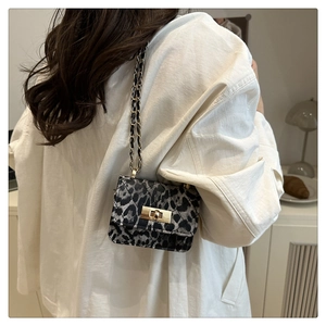 Mini animal print crossbody bag with chain strap shown in a stylish lifestyle cafe setting