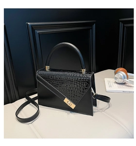 Détail du sac à main noir en similicuir avec motif crocodile et fermoir en métal doré