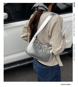 Outdoor street style view of model wearing a silver metallic finish underarm shoulder bag