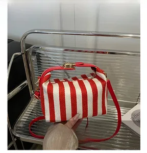 Close-up of red and white striped canvas bag with golden metal twist lock and thin strap