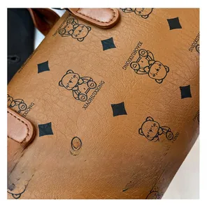 Détail du cuir litchi marron avec imprimé d'ours et losanges sur le sac Boston
