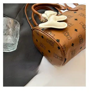 Gros plan du sac Boston marron avec imprimés ours et un pendentif ours blanc