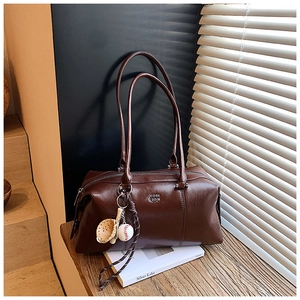 Detail view of dark brown faux leather Boston bag with sports charms and clear texture