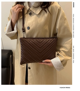 Detail of dark brown V-quilted crossbody bag with silver rivet studs and slim shoulder strap
