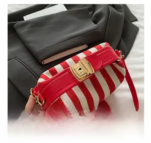 Close-up of red and white striped canvas tote with a premium gold metal lock detail