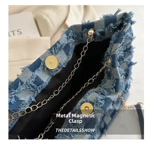 Détail de la boucle magnétique dorée et de la bandoulière chaîne du sac en denim