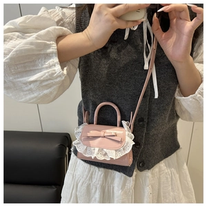 Close-up of pink patent leather handbag with bow and delicate lace trim detail