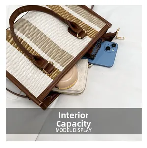 Internal capacity of striped woven tote bag showing phone, wallet, and perfume