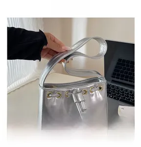Detail view of silver underarm bag with golden eyelets and drawstring closure mechanism