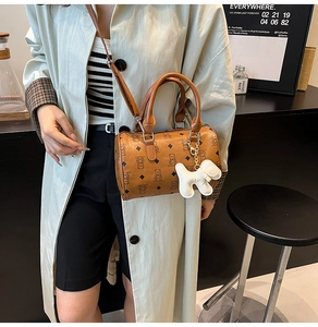 Détail du sac cylindrique marron avec motifs d'ours et petit pendentif chiot blanc