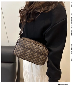 Close-up of a stylish brown monogram small square crossbody bag worn by a female model.