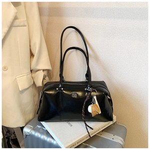 Detail of black glossy leather bowling bag with silver logo and baseball glove charm